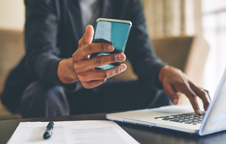 Person using laptop and holding a phone